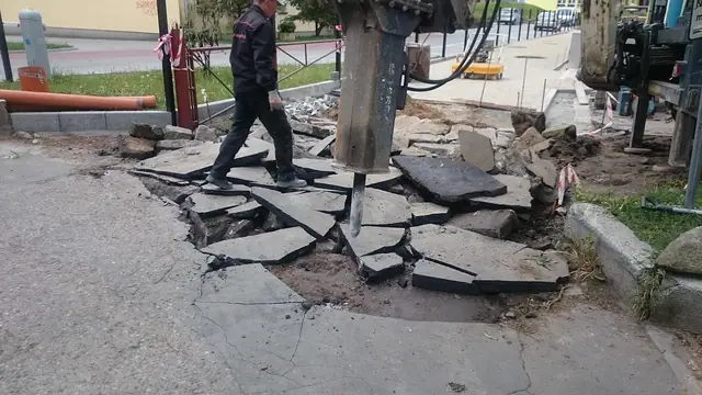 Pracownik idzie po fragmencie rozbitej starej nawierzchni z widocznym ubytkiem