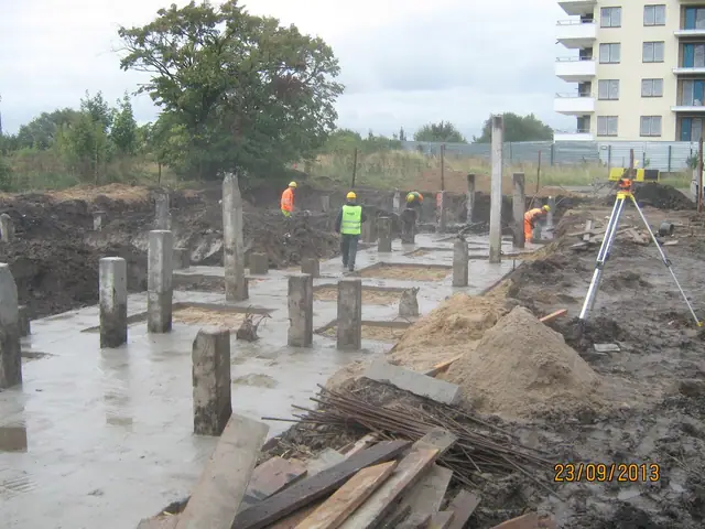 Betonowe słupy fundamentowe i geodeta z niwelatorem na wykopie pod Osiedle pod Lipami w Kołobrzegu