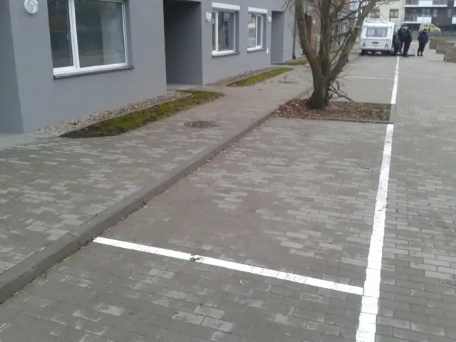 Świeżo ułożona kostka brukowa chodnika przy budynku z białą linią miejsca parkingowego