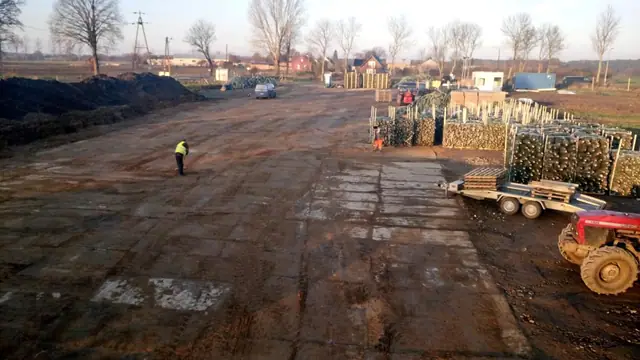 Gotowy utwardzony plac składowy z zaparkowanym ciągnikiem i spaletowanym towarem