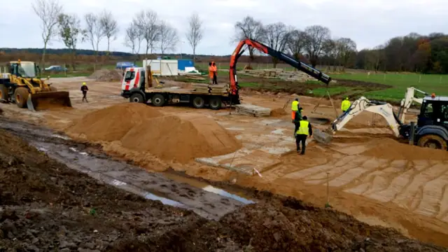 Pompa do betonu i ekipa wylewają fundament na piaszczystym placu składowym