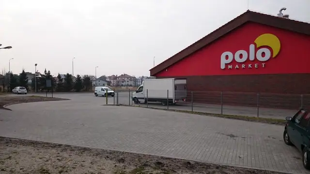 Gotowy parking z kostki brukowej przed budynkiem marketu Polo z czerwonym dachem