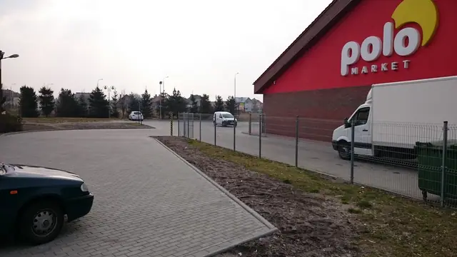 Parking z kostki brukowej przy markecie Polo z zaparkowaną furgonetką i osobowym autem