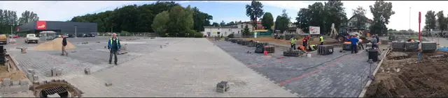 Widok z lotu ptaka na częściowo wyłożony kostką plac parkingowy przy markecie