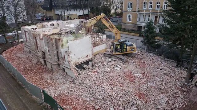 Koparka kontynuuje wyburzanie pozostałości ścian budynku, gruz zalega na całej działce