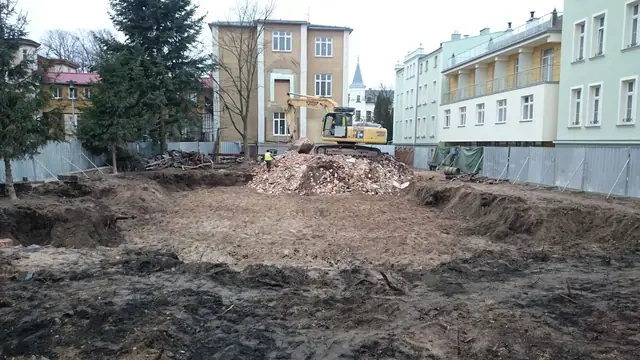 Koparka wygładza teren po rozbiórce budynku obok sąsiednich kamienic