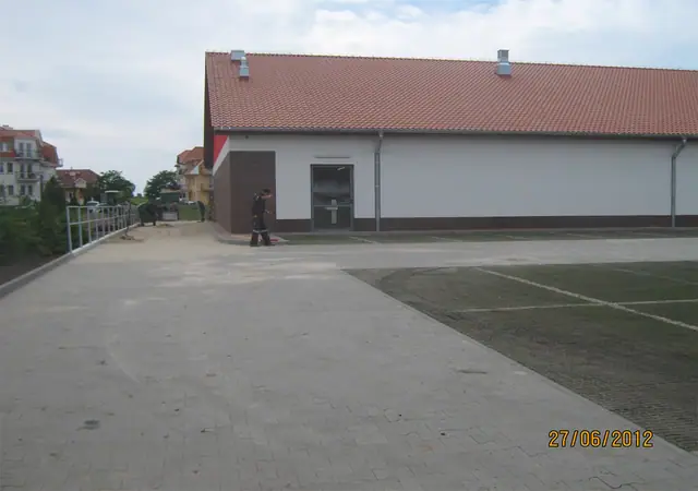 Plac przed budynkiem marketu w trakcie brukowania kostką betonową