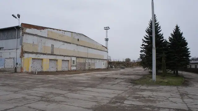 Opuszczony żółto-biały magazyn na betonowym placu terenu portowego