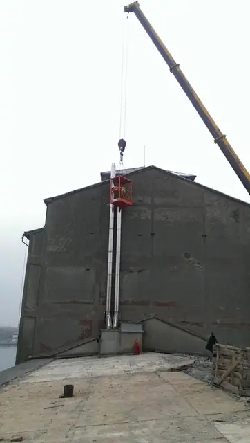 Podnośnik koszowy przy elewacji wysokiego budynku podczas prac rozbiórkowych