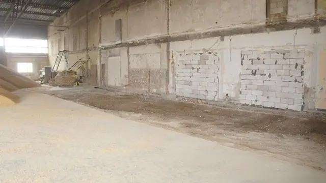 Wnętrze hali magazynowej z odsłoniętymi białymi cegłami przed rozbiórką