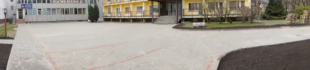 Narożnik dużego placu z kostki brukowej z ciemną obwódką przygotowaną pod klomb