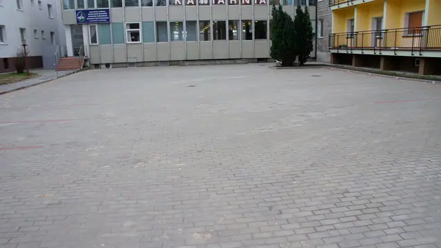 Duży plac z kostki brukowej przed żółtym budynkiem z napisem Kawiarnia
