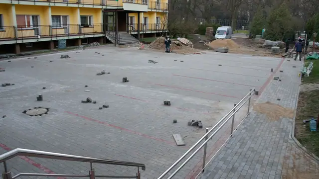 Ukończony fragment placu z kostki brukowej z metalowymi studzienkami, widok od schodów