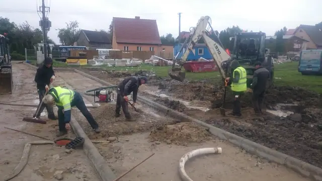 Okrągły trawnik pośrodku wybrukowanego placu manewrowego przy zabudowaniach sanktuarium