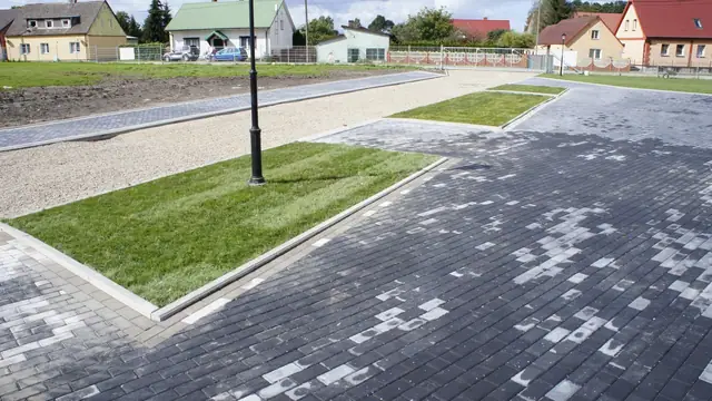 Wybrukowany plac z trawiastą wyspą i latarnią, ukończony etap zagospodarowania terenu