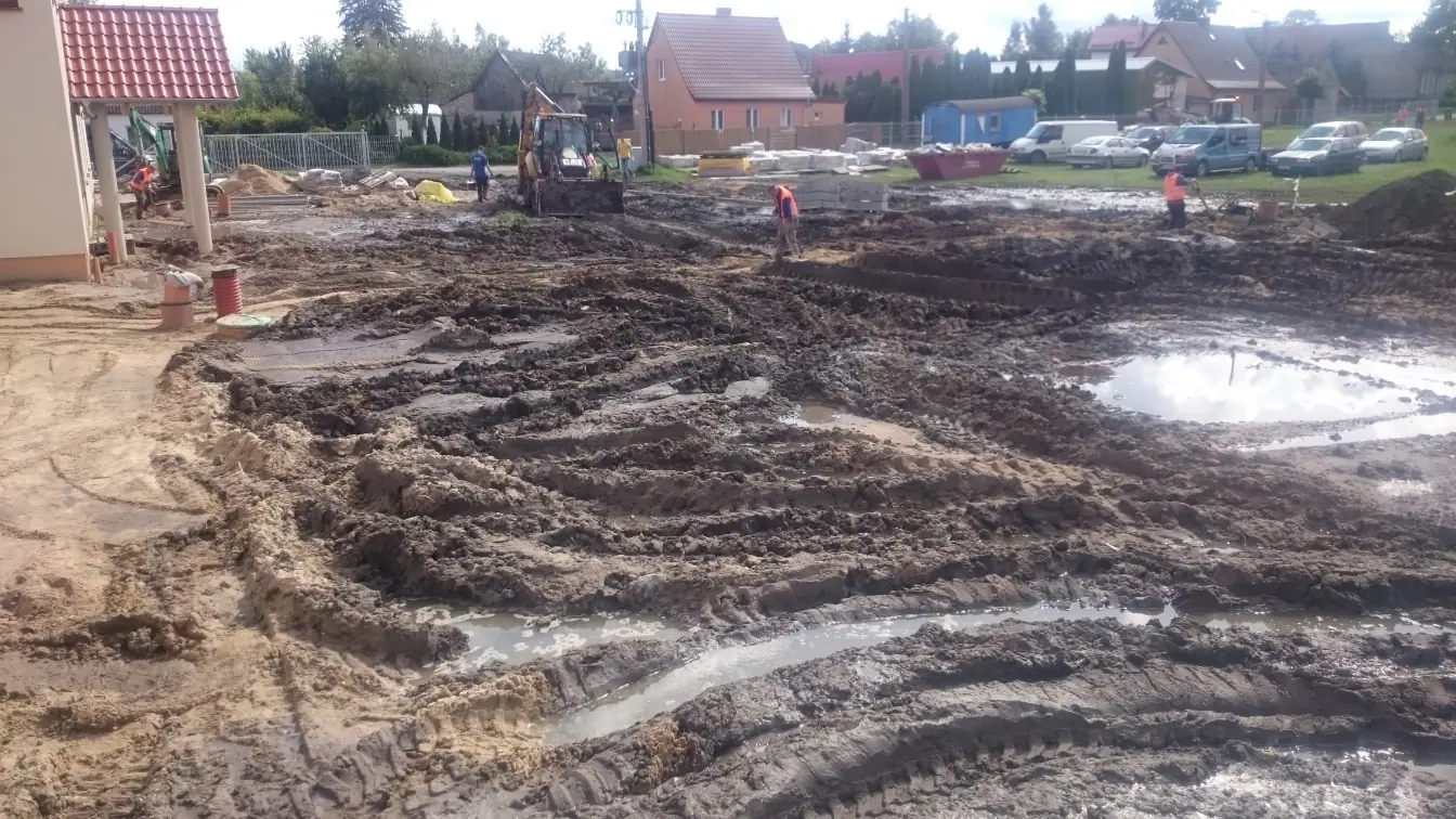 Rozjeżdżony, błotnisty plac budowy z głębokimi koleinami przy Sanktuarium w Skrzatuszu – rozmokły grunt przed wykonaniem odwodnienia działki