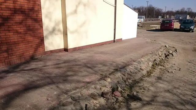 Rozbita stara nawierzchnia z kamienia usuwana wzdłuż ceglanej ściany restauracji Fishka Fiszka