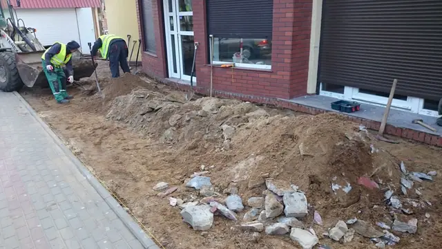 Ekipa usuwa hałdę gruzu betonowego leżącą obok już wykończonego chodnika