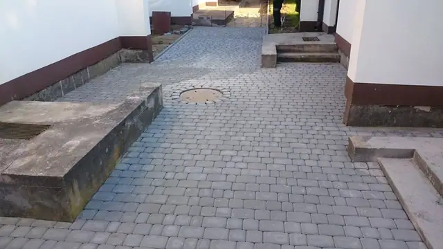 Gotowy chodnik z kostki brukowej między budynkami ośrodka wypoczynkowego w Sianożętach ze studzienką