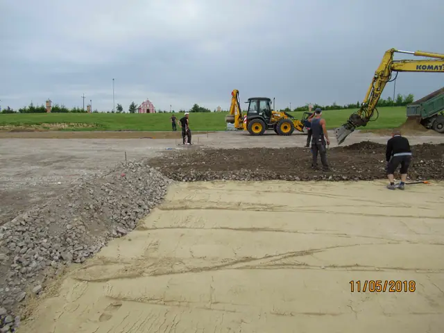 Dwie koparko-ładowarki kształtują zakrzywioną krawędź podbudowy żwirowej placu