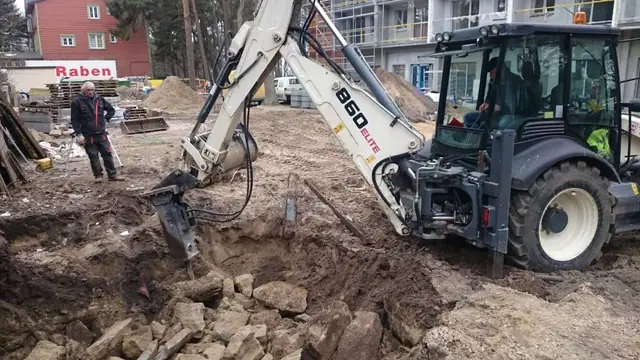 Koparka z młotem hydraulicznym kruszy stary gruz betonowy na terenie inwestycji