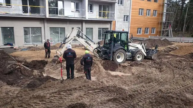 Mini koparka kopie wykop przy budynku z balkonami w ramach zagospodarowania terenu