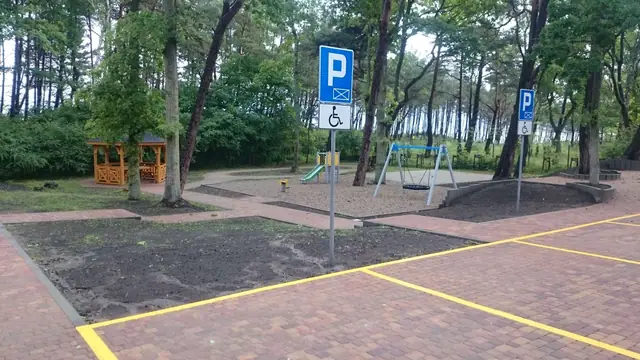 Znaki miejsc parkingowych dla niepełnosprawnych przy alejce prowadzącej do placu zabaw
