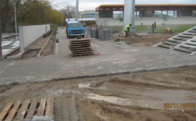 Plac przed trybunami w trakcie brukowania, ciężarówka i palety kostki na miejscu