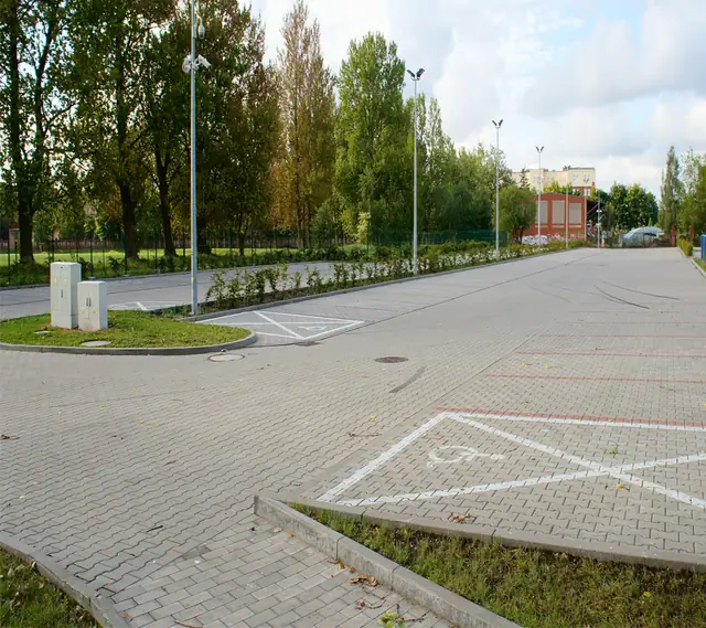 Parking z kostki brukowej z oznaczonym miejscem dla niepełnosprawnych przy stadionie