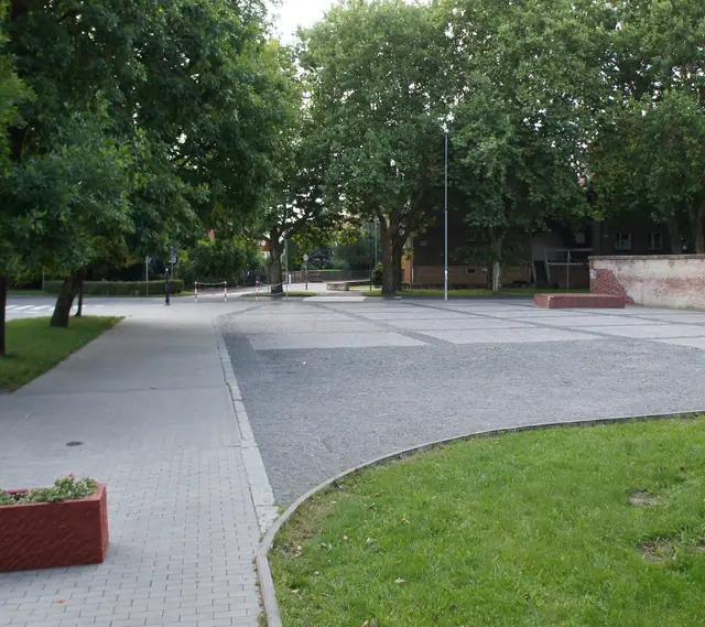 Plac z kostki brukowej między trawnikami z donicami na terenach zielonych przy stadionach