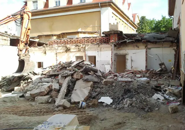 Gruz po wyburzeniu fragmentu starego budynku szpitalnego w Koszalinie, w tle pracująca koparka