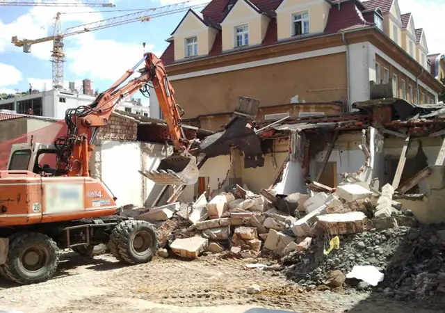 Koparka rozbiera stary murowany budynek na terenie Szpitala Wojewódzkiego w Koszalinie