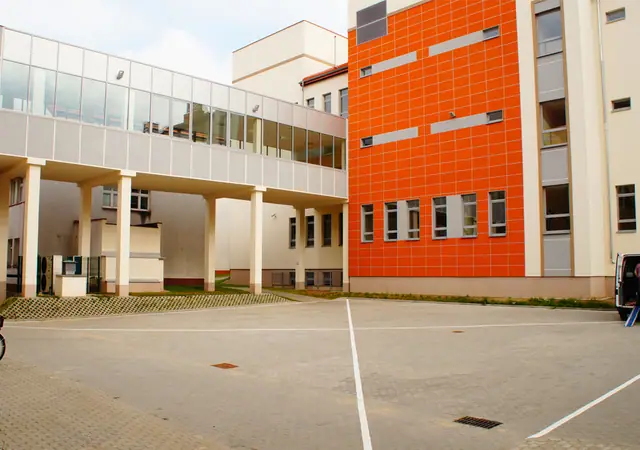 Utwardzony plac przy nowoczesnym pomarańczowo-białym łączniku Szpitala Wojewódzkiego w Koszalinie