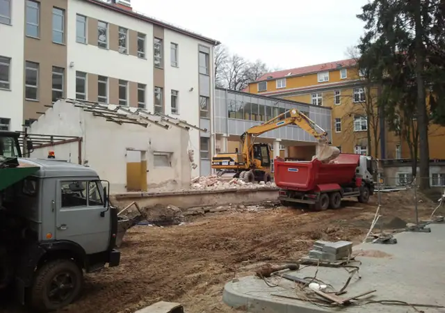 Samochód ciężarowy i koparka przy wyburzonym budynku obok Szpitala Wojewódzkiego w Koszalinie