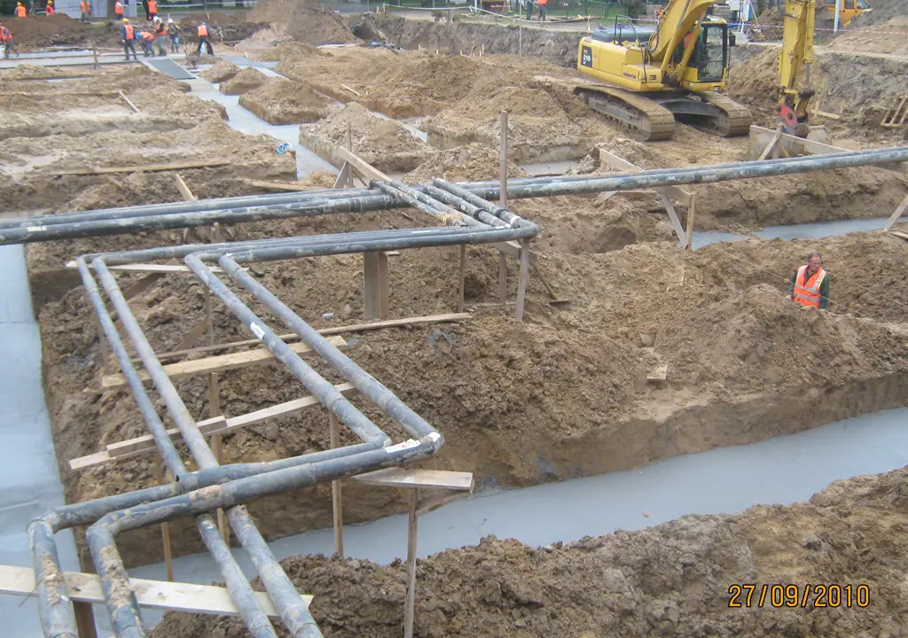 Wykop pod przyłącze z ułożonymi na podporach rurami instalacyjnymi