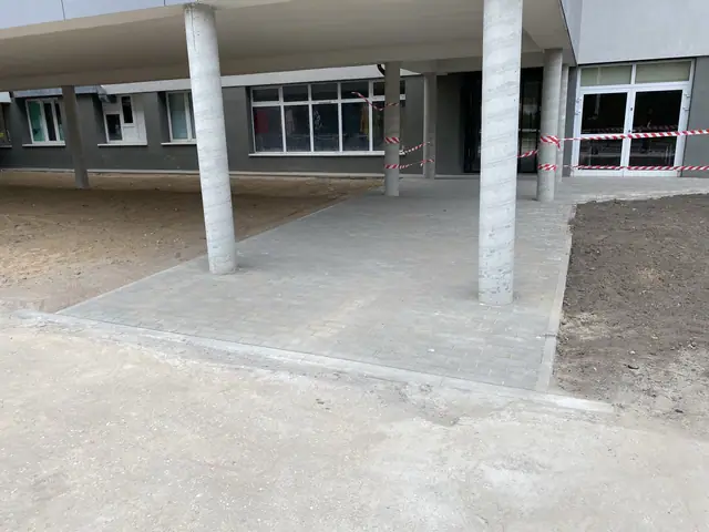 Nowe betonowe filary podcienia i świeża nawierzchnia przy wejściu do pawilonu szpitala