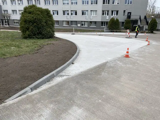 Łukowy krawężnik i świeża nawierzchnia betonowa przy trawniku na terenie szpitala