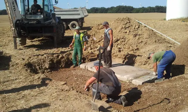 Robotnicy montują betonową płytę fundamentową drogi dojazdowej obok turbiny wiatrowej