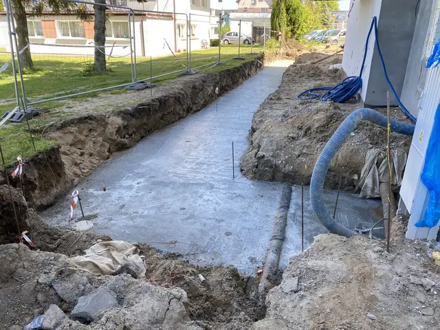 Świeżo wylany betonowy chodnik w wykopie z wystającymi prętami zbrojeniowymi