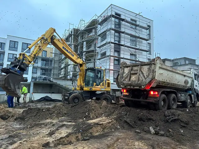 Koparka Komatsu ładuje ziemię na wywrotkę podczas prac ziemnych na placu budowy
