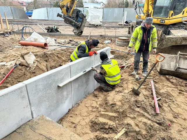 Ekipa w kamizelkach odblaskowych montuje prefabrykowany mur oporowy z betonowych płyt