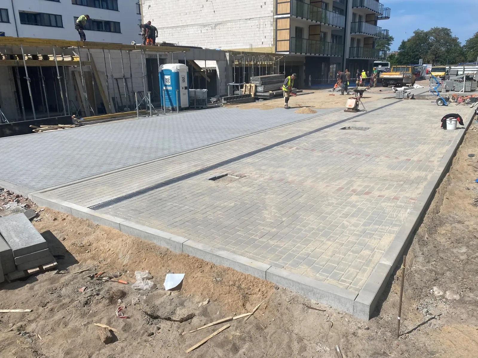 Gotowy plac z jasnej kostki brukowej przed nowo budowanym budynkiem mieszkalnym przy ul. Bałtyckiej