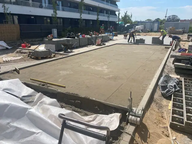 Robotnicy przygotowują betonową podbudowę pod nawierzchnię otoczoną prefabrykowanymi krawężnikami