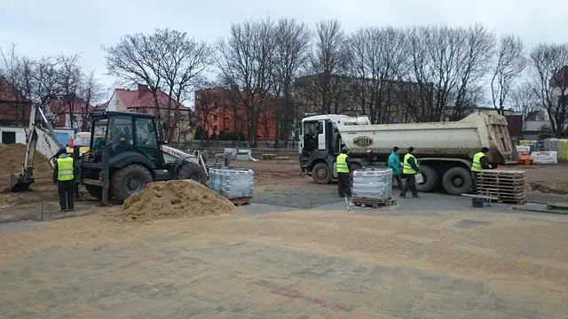 Koparka i ciężarówka dostarczają kruszywo na plac budowy parkingu