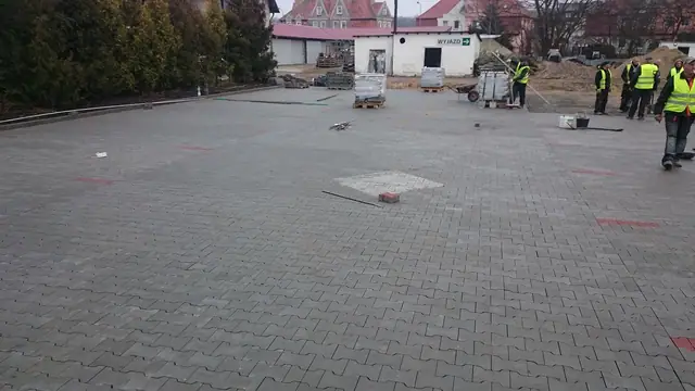Ukończony fragment parkingu z kostki betonowej, w tle zielona hala centrum ogrodniczego